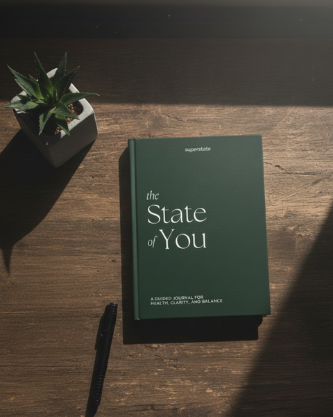 Guidet journal "The State of You" fra Superstate, designet for helse, klarhet og balanse, plassert på et trebord med en plante og penn.