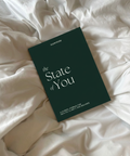 The State of You journal fra Superstate, liggende på et mykt, hvitt sengeteppe, som fremmer helse, klarhet og balanse.